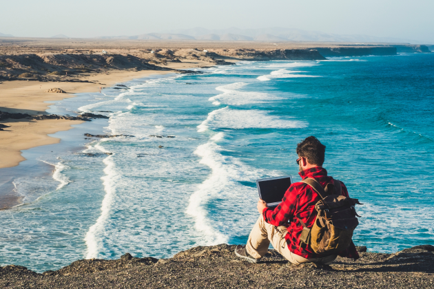 homem com computador e vista para a praia